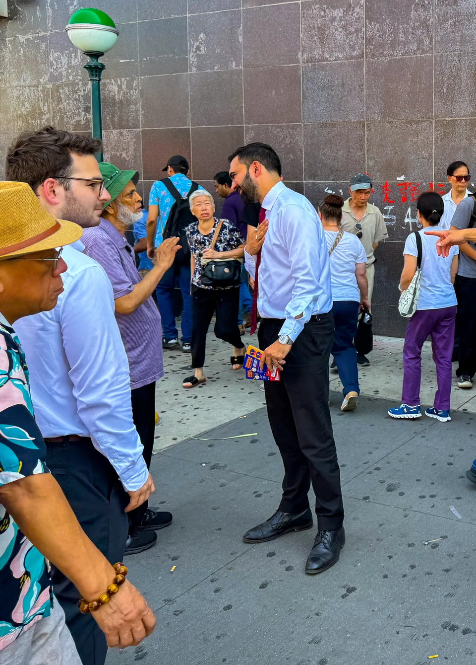 Zohran Mamdani campaigning on a street in Flushing
