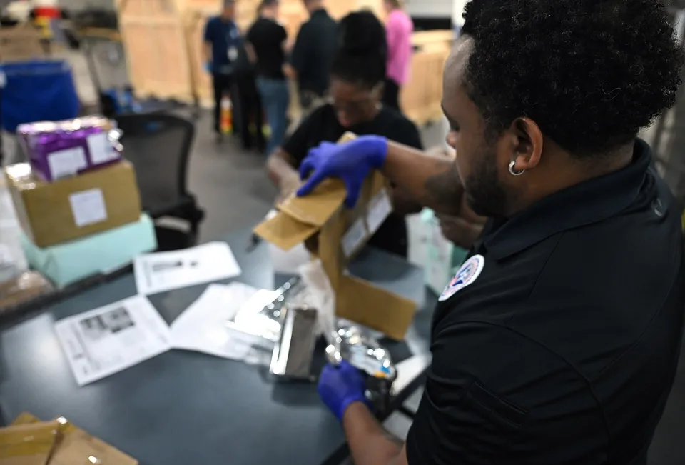 CBP officers inspecting international mail packages at the JFK International Mail Facility